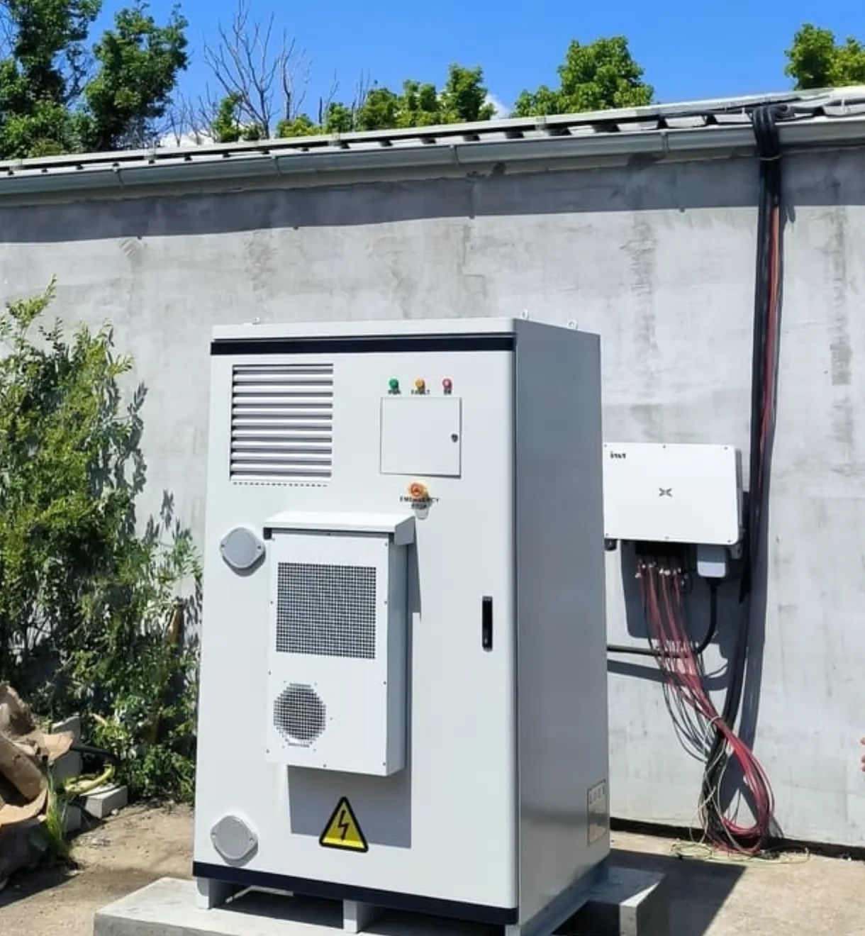 Battery storage cabinet installed beside third-party wall-mounted conversion equipment on the same AC bus