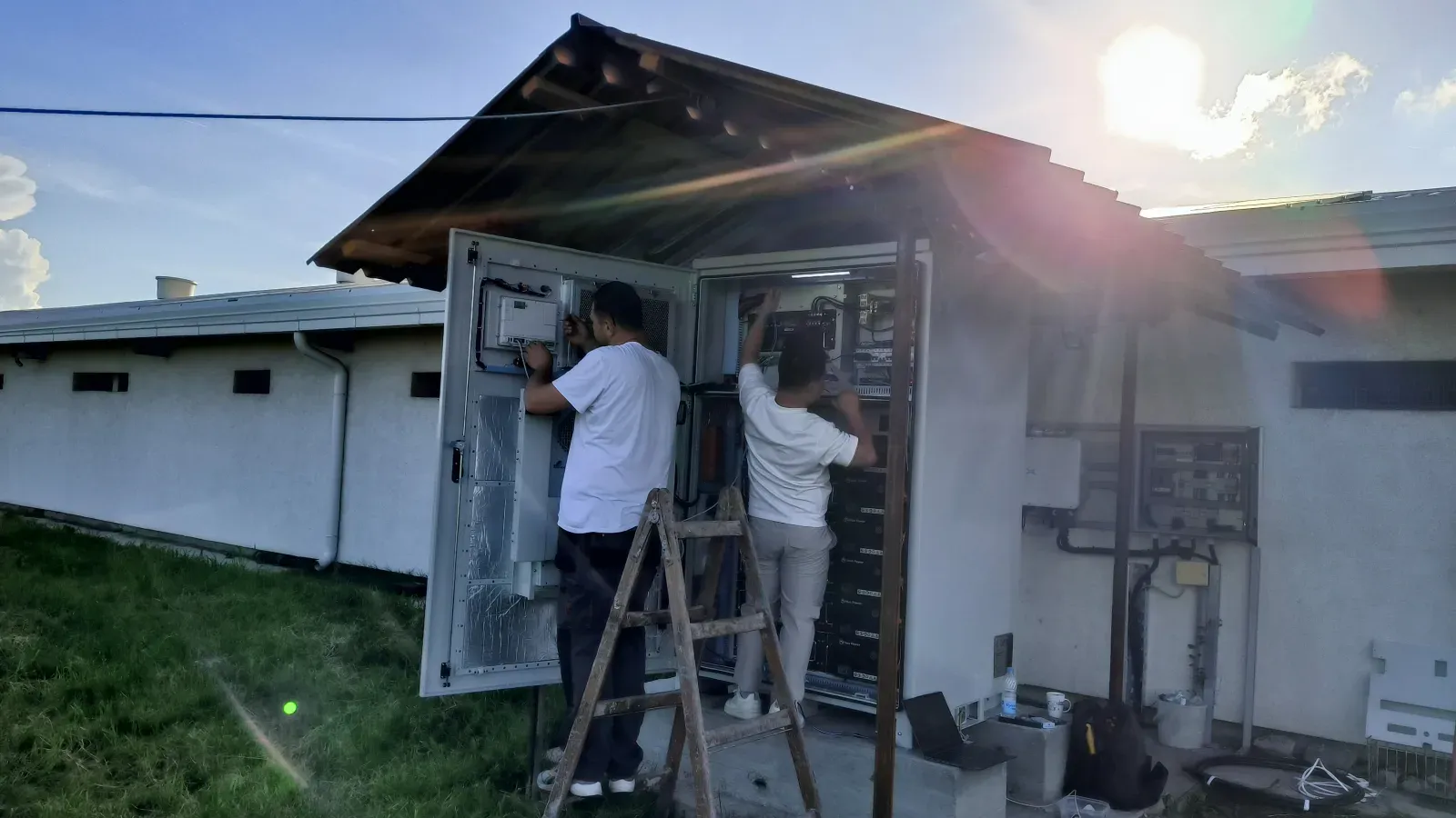 Two engineers checking an open battery cabinet during commissioning, the step that confirms the modelled performance is real