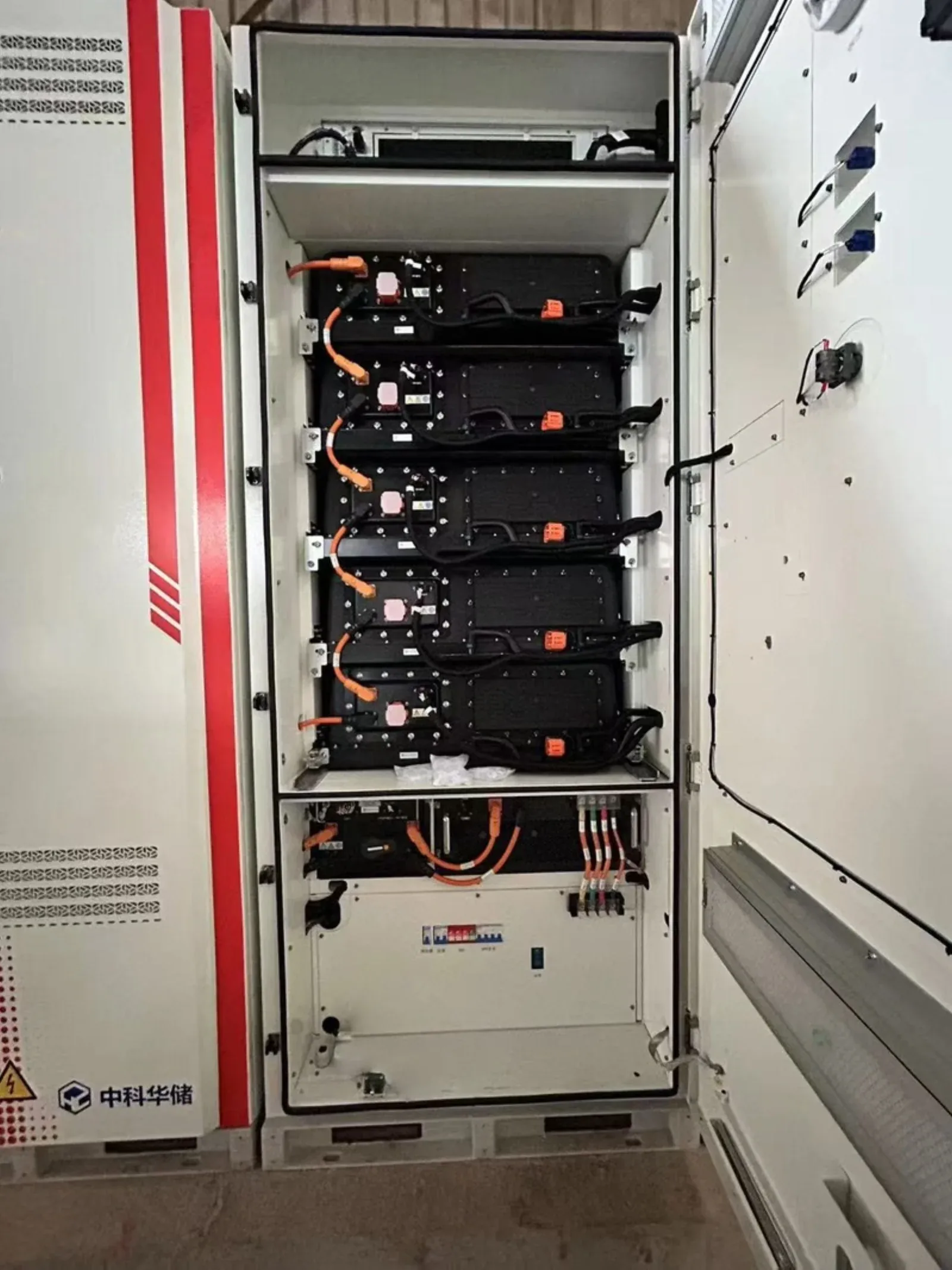 The interior of a battery storage cabinet showing cell modules in racks and BMS wiring, the cost lines a specification change moves first